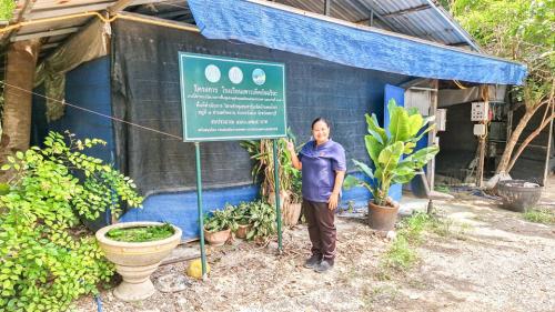 เจ้าหน้าที่พัฒนาชุมชนยืนด้านหน้าโรงเรือนเพาะเห็ด